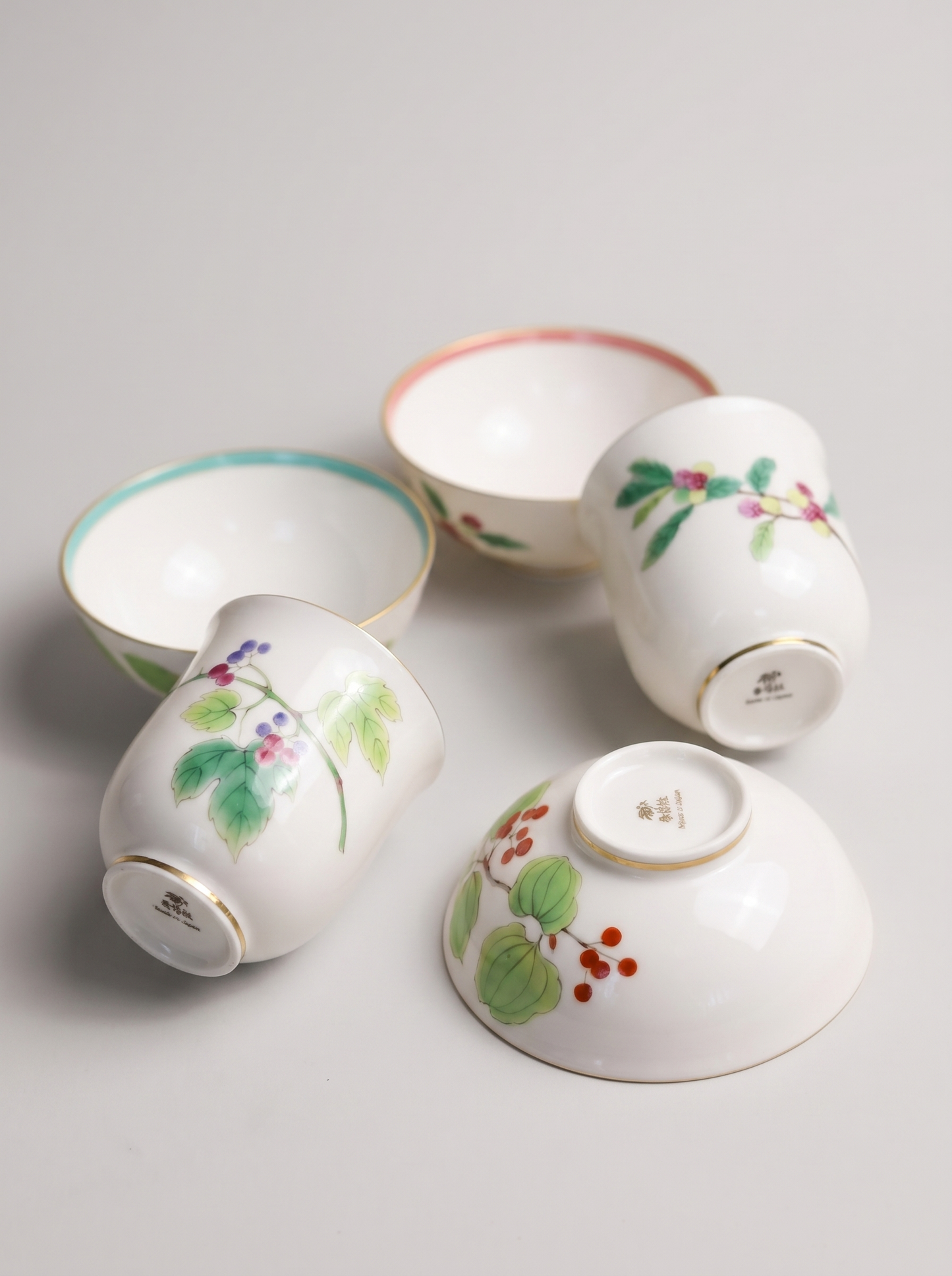 Set of four Japanese koransha porcelain cups with floral designs on a light gray background