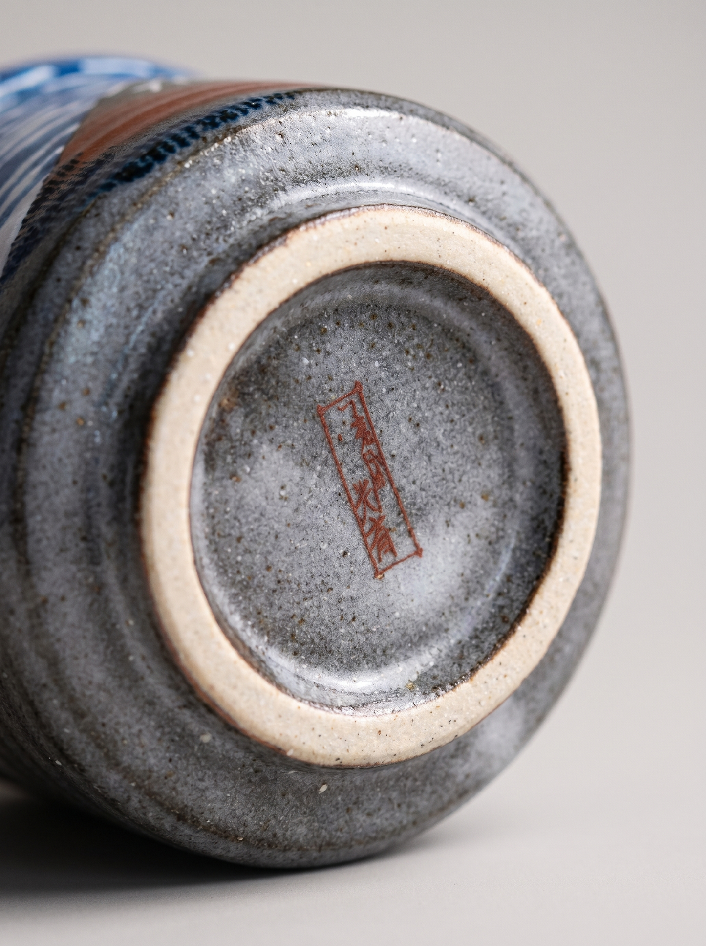 Close-up of a ceramic cup with a visible brand logo on a gray background