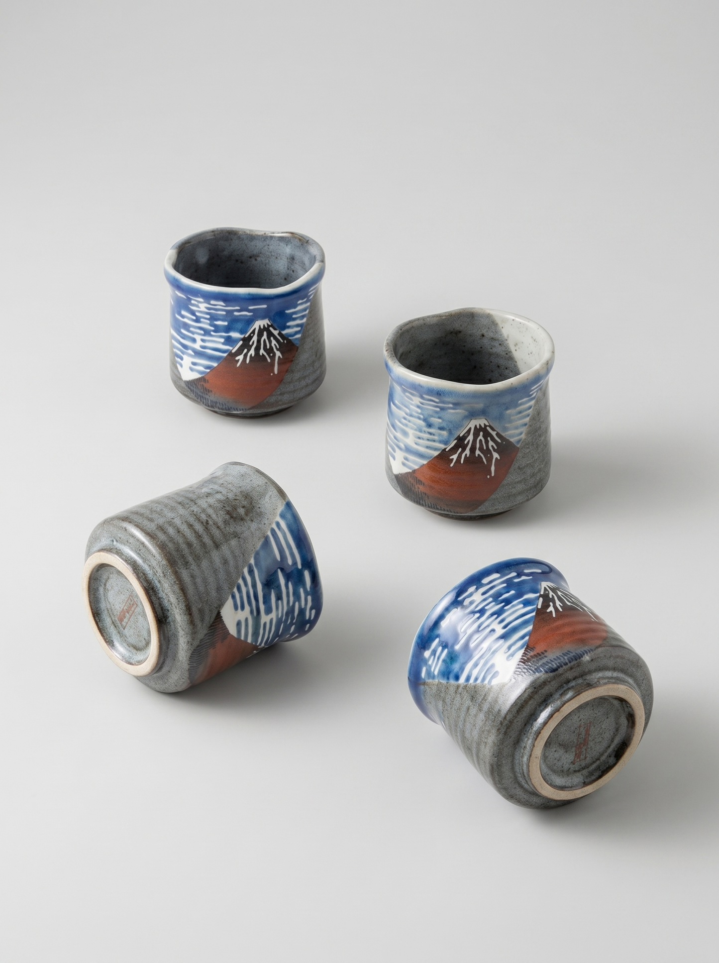 Four ceramic cups with Fuji mountain  design on a light gray background