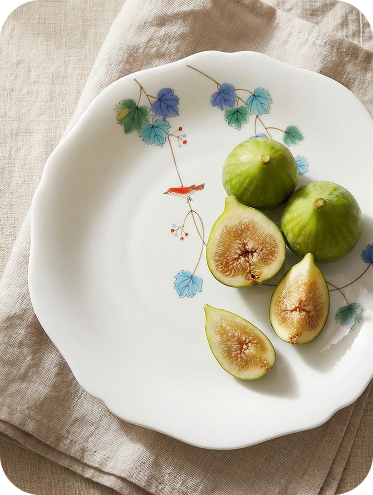 Figs on a decorative plate with a hand-painted illustration "bird on a branch" on a beige cloth background