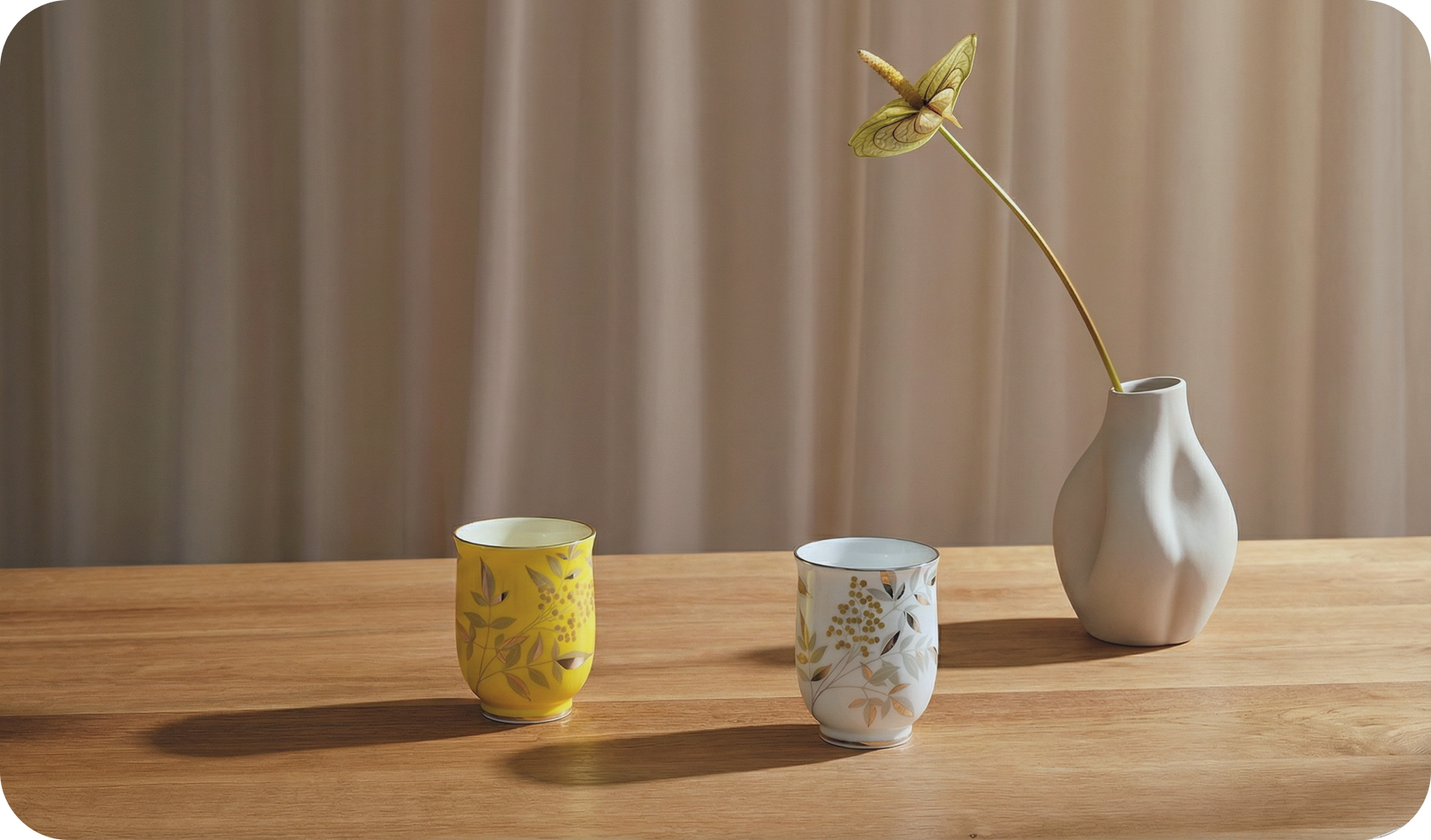 Two Japanese porcelain teacups and a vase on a wooden table with a neutral background