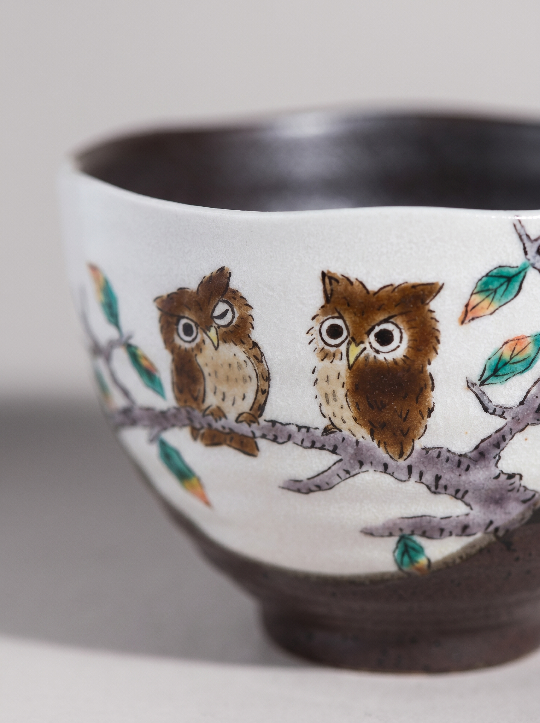 Close up of a japanese ceramic bowl with owl design on a plain background