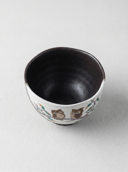 Japanese ceramic cup with owl design on a light gray background top view