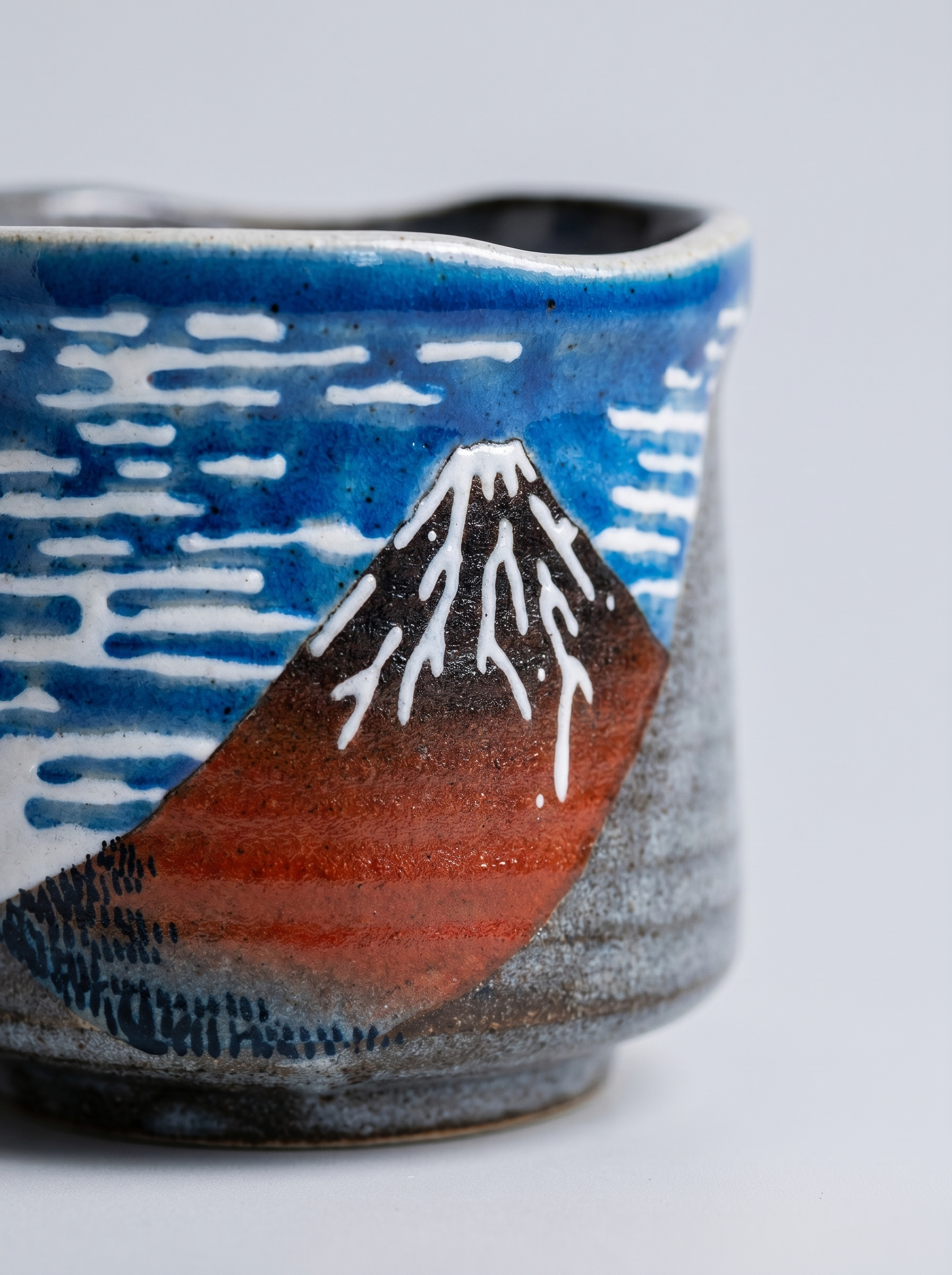 Close up of Kutani ceramic cup with Red Mount Fuji design on a light gray background