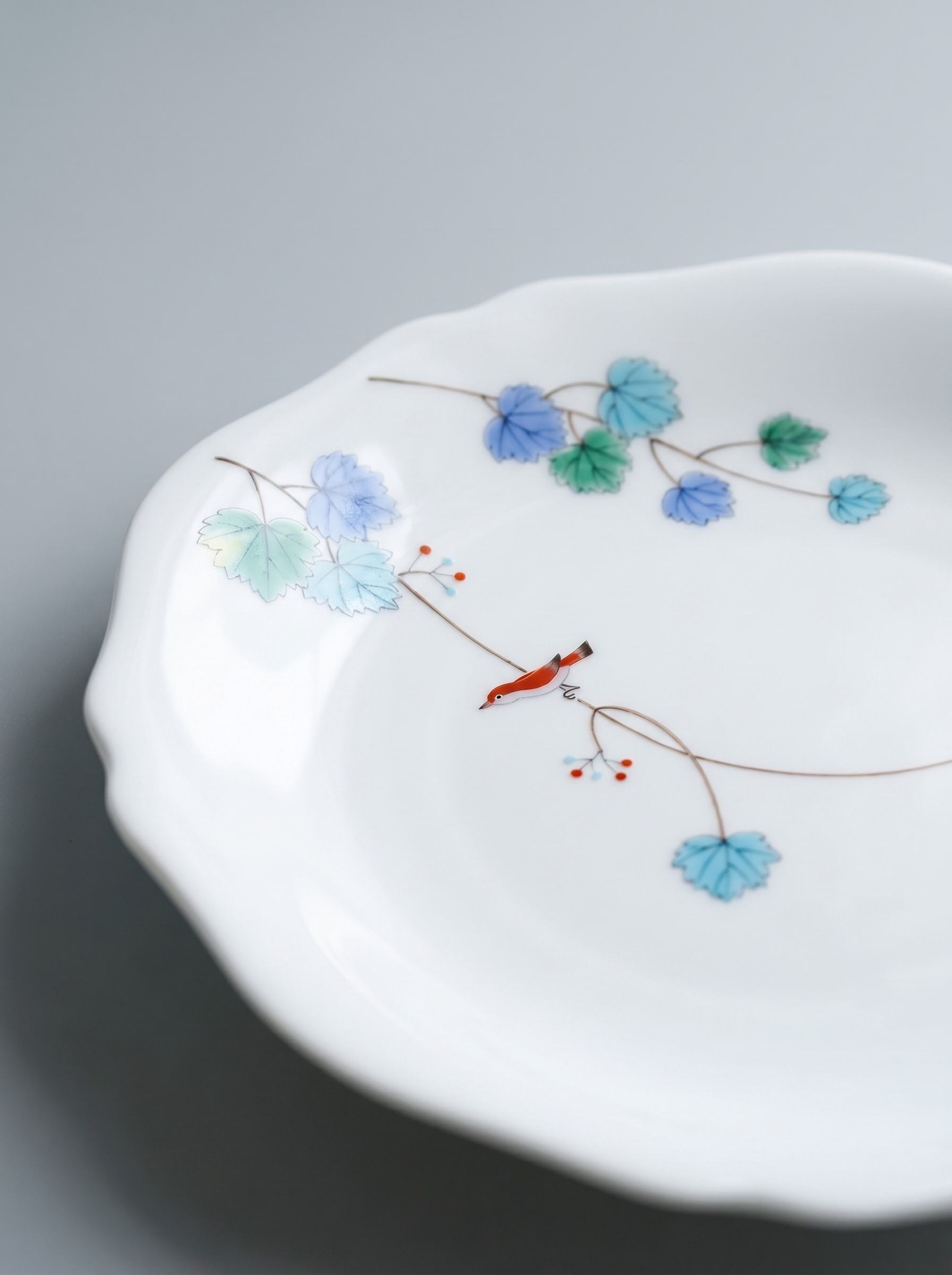 Close up of Japanese koransha porcelain dinner plate with floral design on a gray background