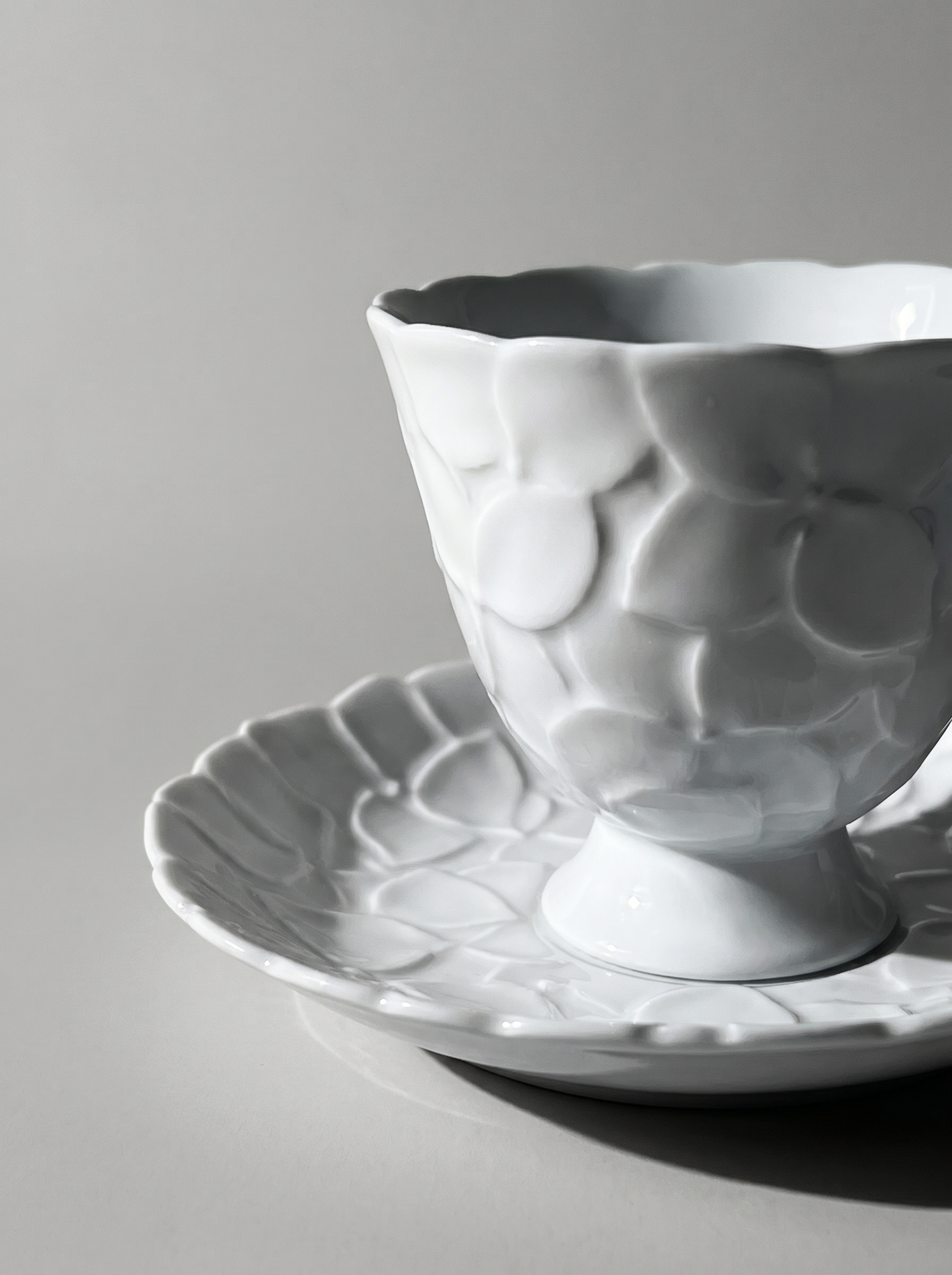 close up of Japanese white koransha teacup with a short handle and a saucer on a sodt grey background