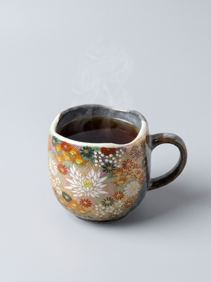 Japanese hanazume ceramic mug with floral pattern on a light gray background filled with black tea