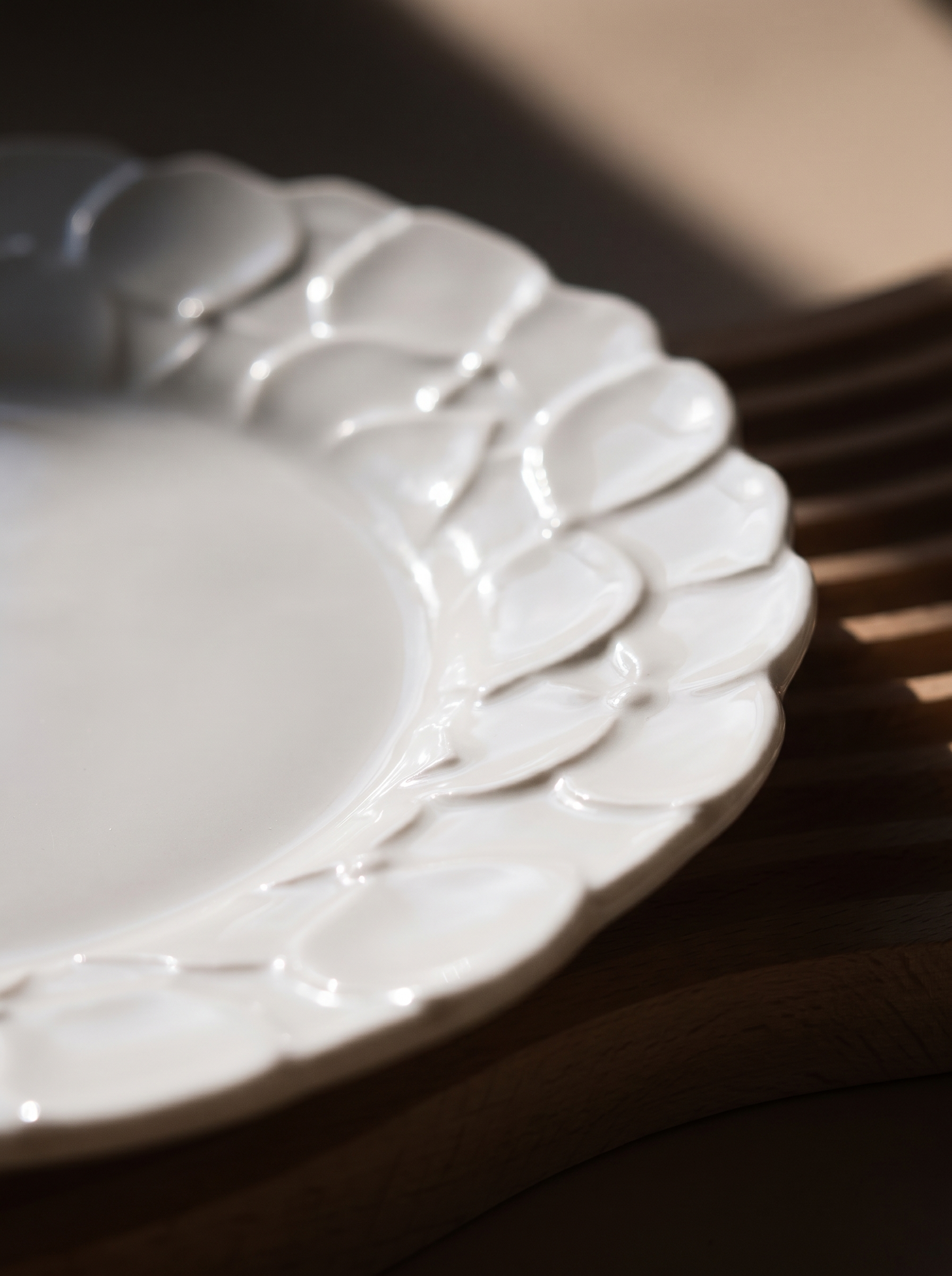 macro view of a white Japanese koransha decorative plate with embossed surface on a beige background, showcasing its relief