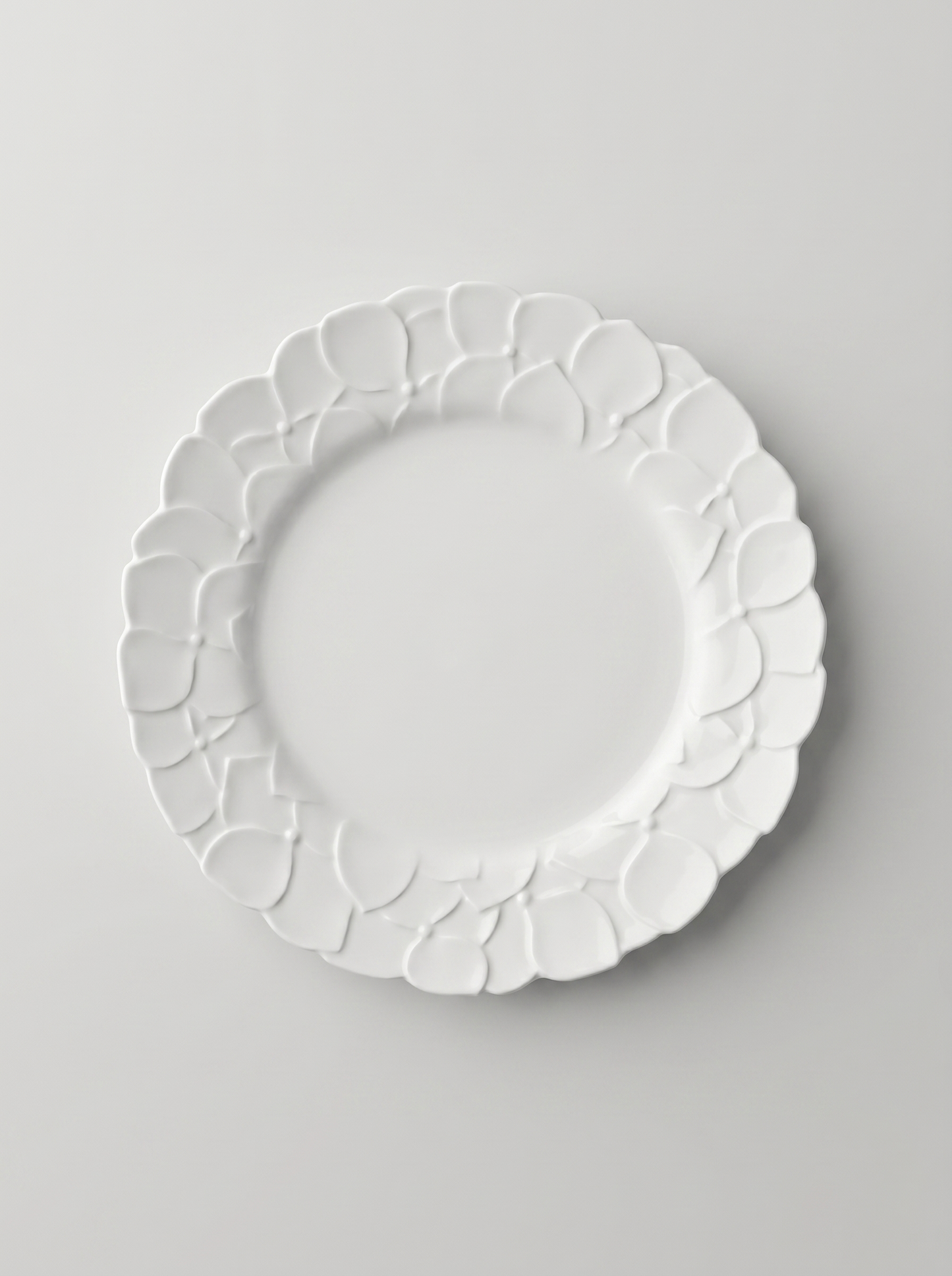 White Japanese koransha decorative plate with embossed surface on a light gray background