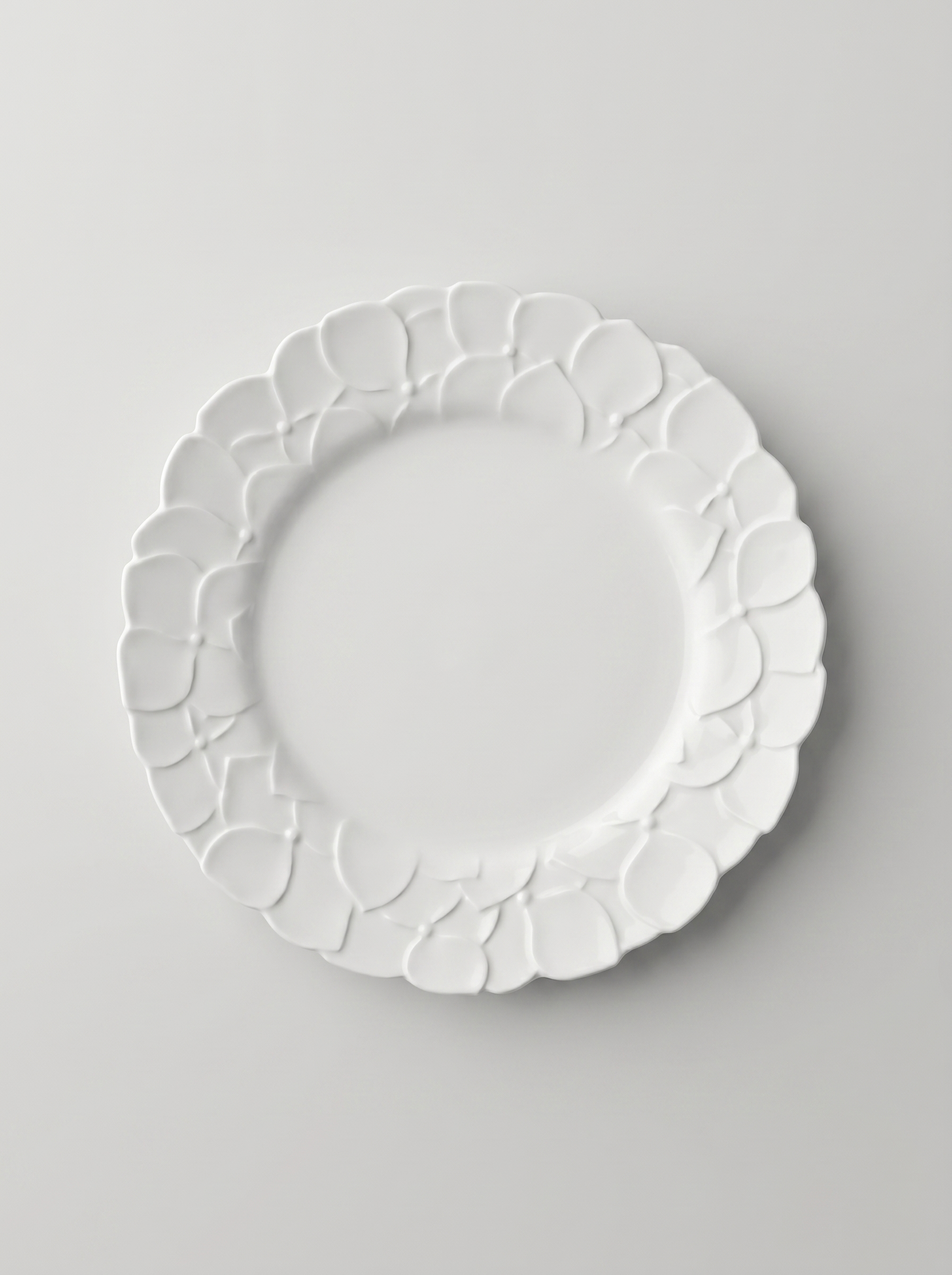White Japanese koransha decorative plate with embossed surface on a light gray background