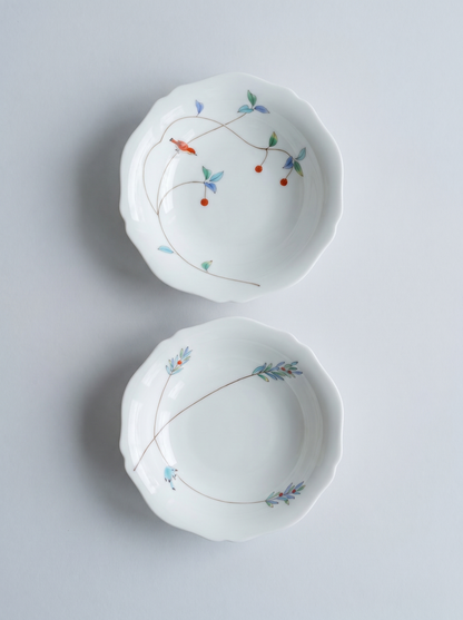 Two white japanese koransha porcelain bowls with floral patterns on a light gray background