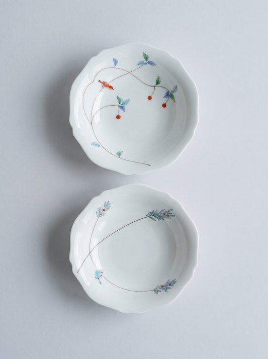 Two white japanese koransha porcelain bowls with floral patterns on a light gray background
