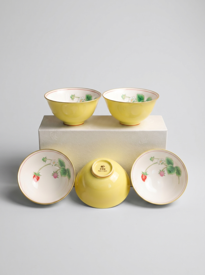 Set of five yellow Japanese koransha porcelain teacups with berry designs on a gray background