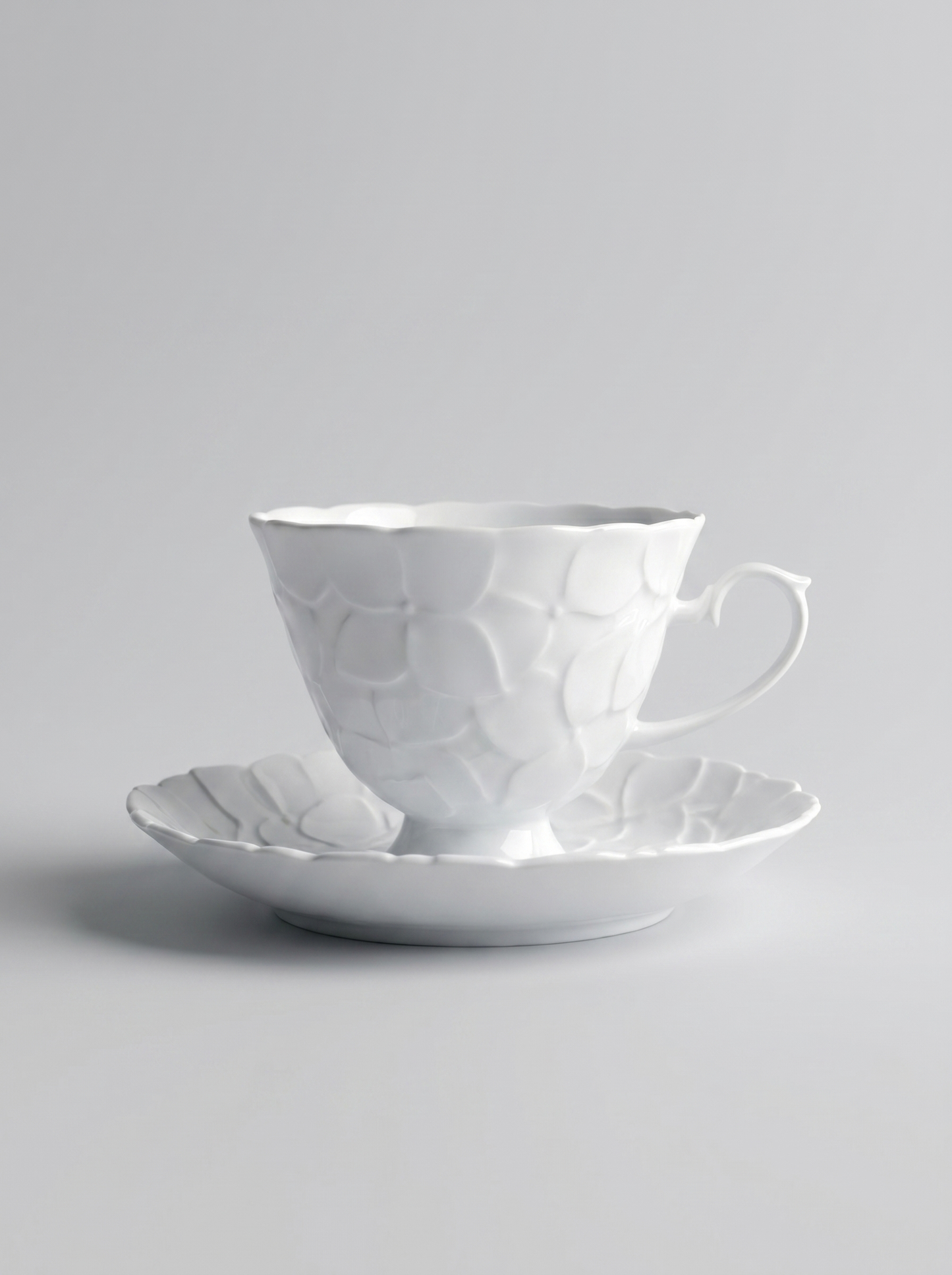 Japanese white koransha teacup with a short handle and a saucer on a sodt grey background