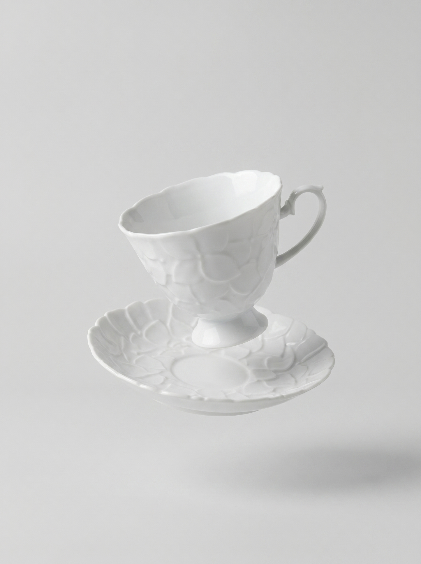 levitating Japanese white koransha teacup with a short handle and a saucer on a sodt grey background