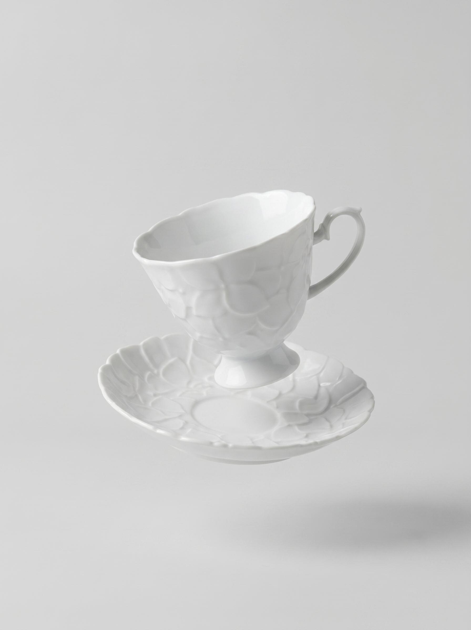 levitating Japanese white koransha teacup with a short handle and a saucer on a sodt grey background