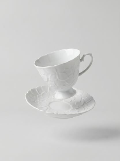 levitating Japanese white koransha teacup with a short handle and a saucer on a sodt grey background