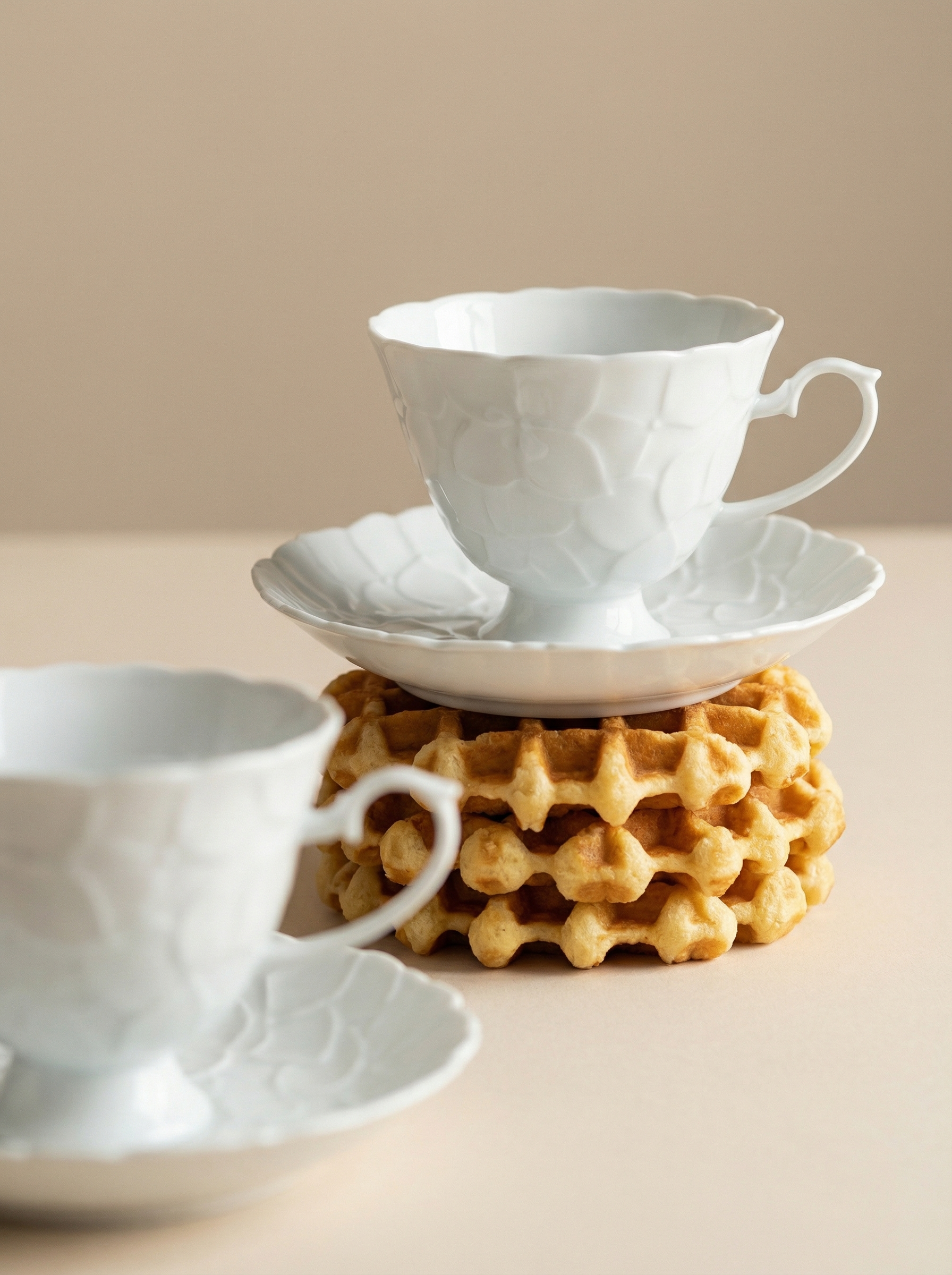 White ceramic teacup and saucer on a waffle-shaped coaster with a beige background