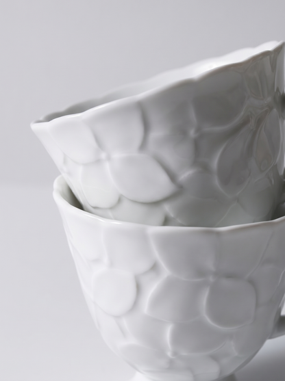 pair of Japanese white koransha teacup with a short handle and a saucer on a sodt grey background