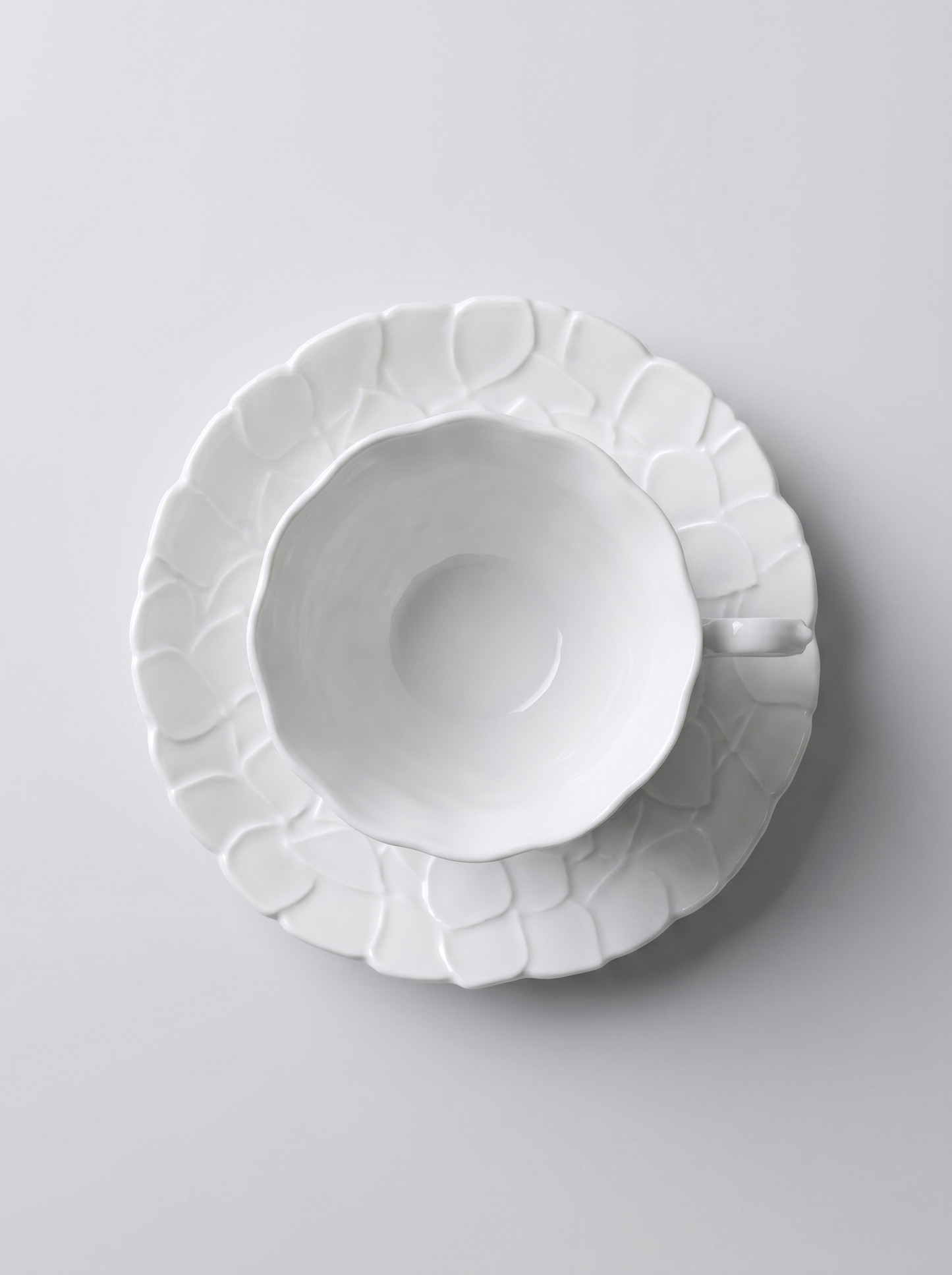 top view of Japanese white koransha teacup with a short handle and a saucer on a sodt grey background