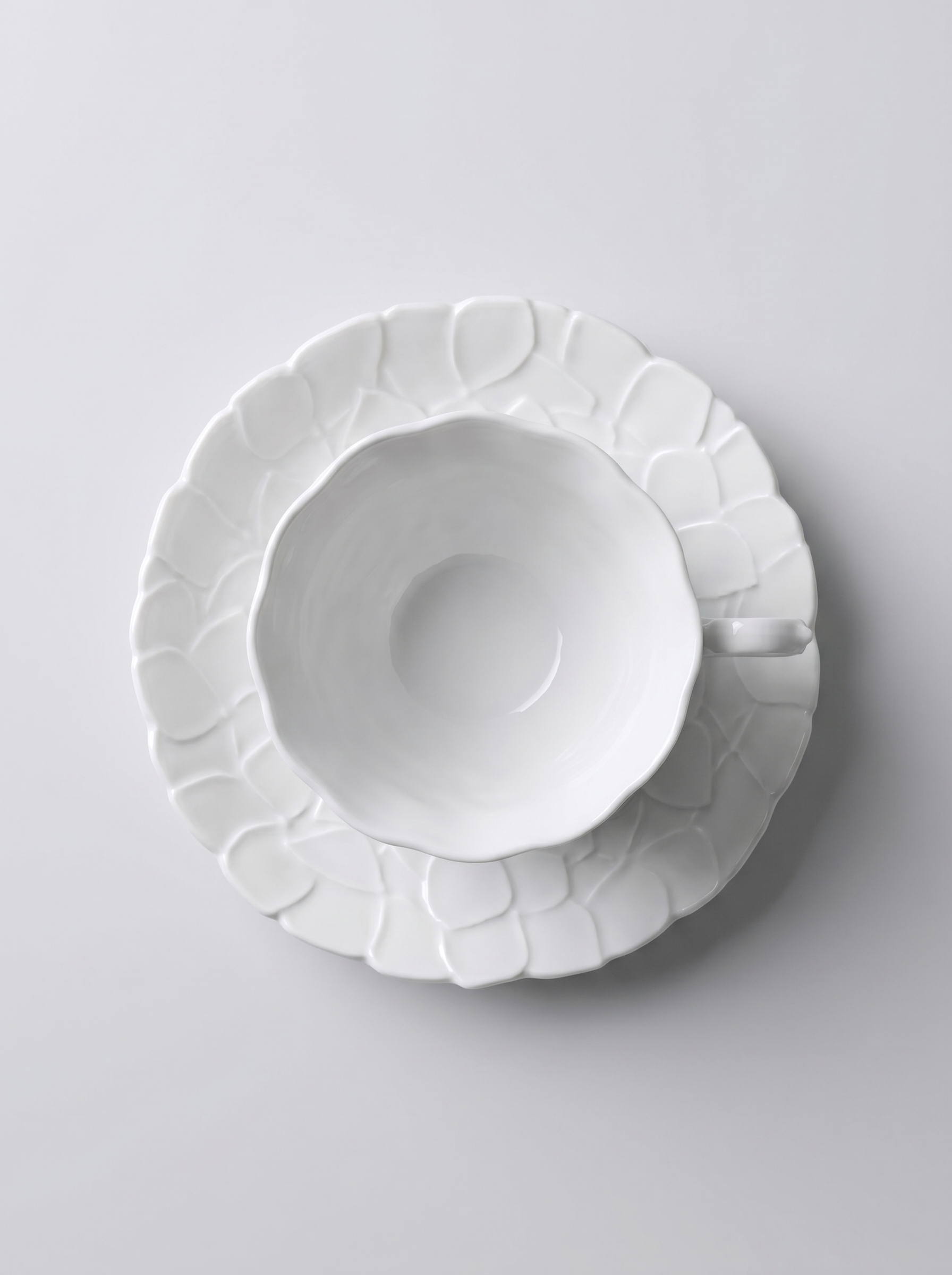 top view of Japanese white koransha teacup with a short handle and a saucer on a sodt grey background