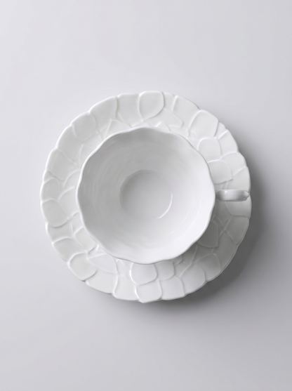 top view of Japanese white koransha teacup with a short handle and a saucer on a sodt grey background