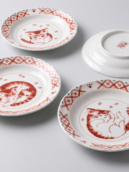 Set of japanese ceramic plates with red cat illustrations on a light gray background