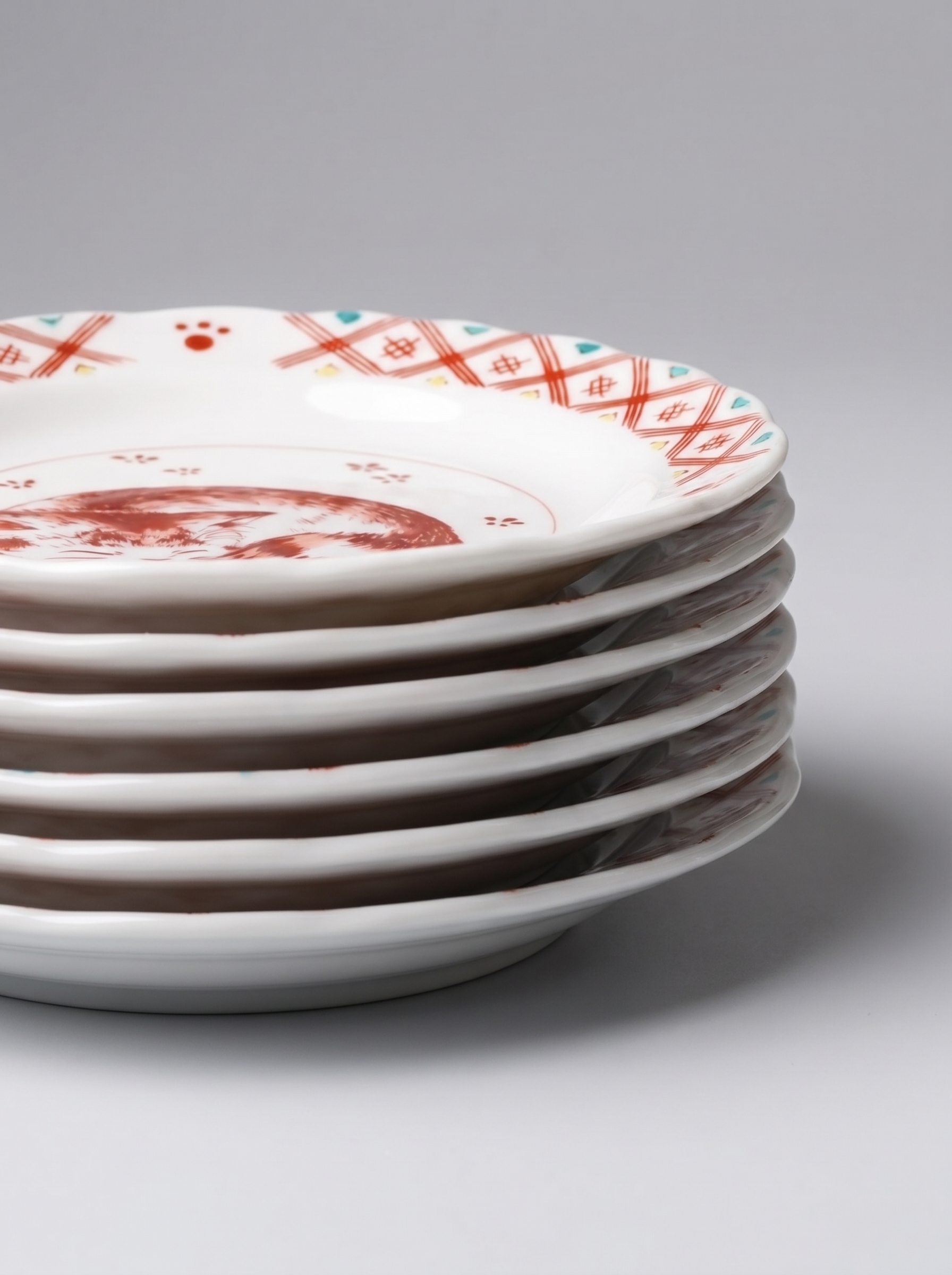 Stack of Japanese ceramic plates with decorative patterns on a light gray background