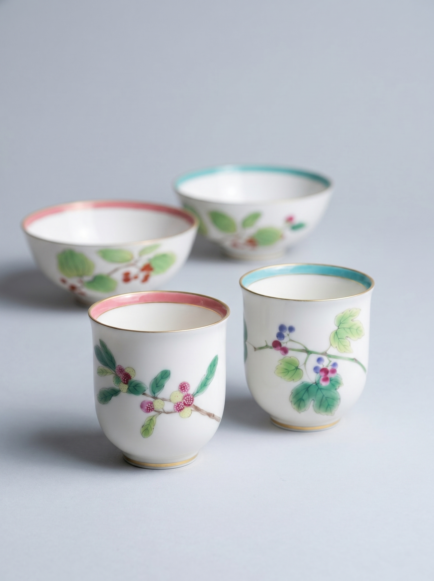 close up of set of four Japanese koransha porcelain cups with floral designs on a light gray background