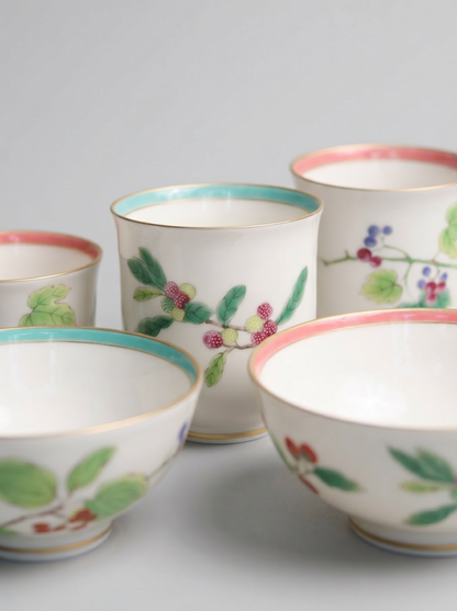 close up of set of four Japanese koransha porcelain cups with floral designs on a light gray background