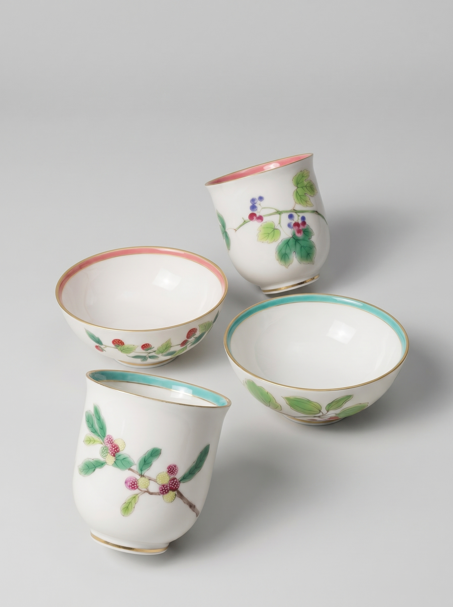 Set of four Japanese koransha porcelain cups with floral designs on a light gray background