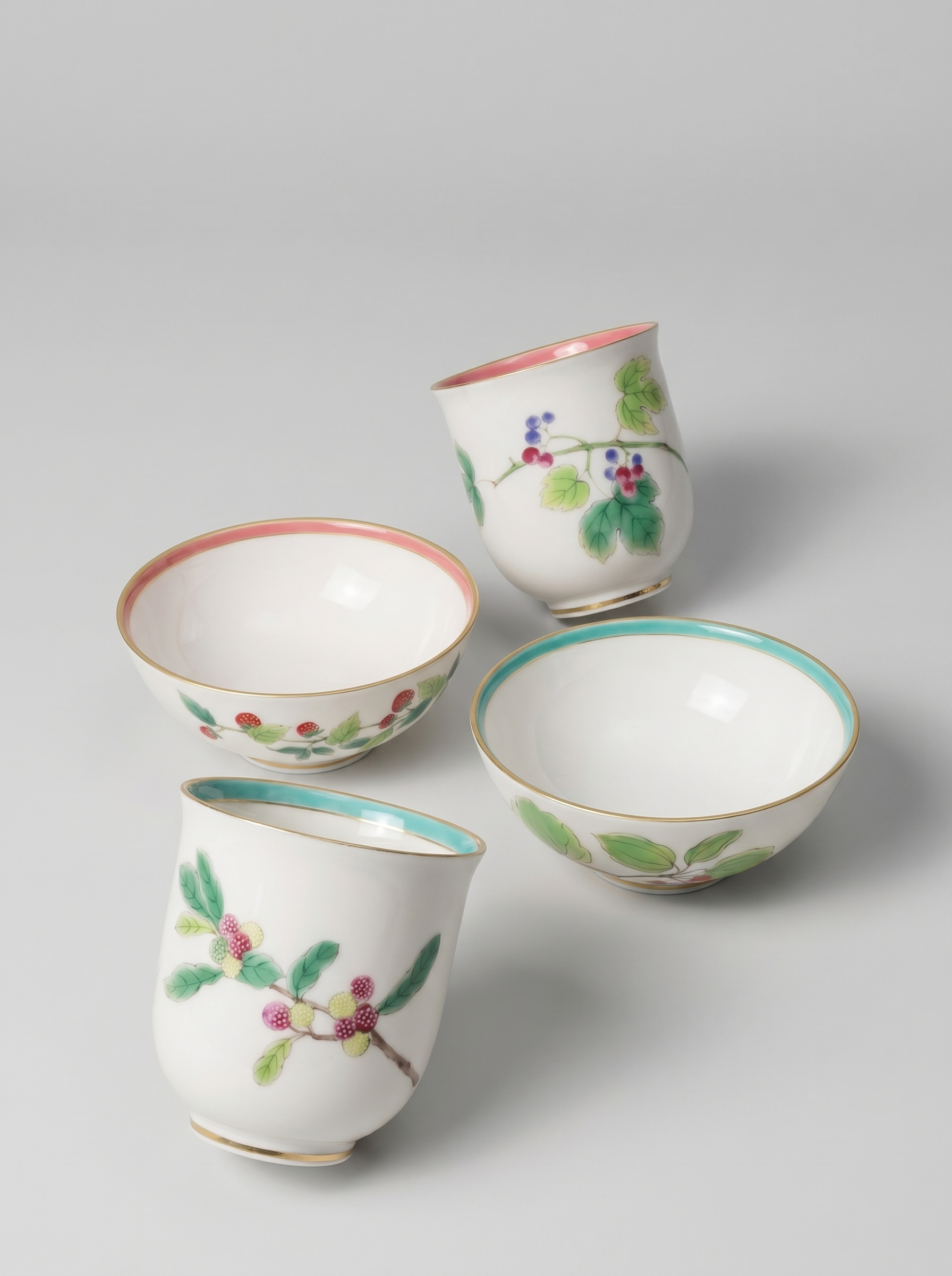 Set of four Japanese koransha porcelain cups with floral designs on a light gray background