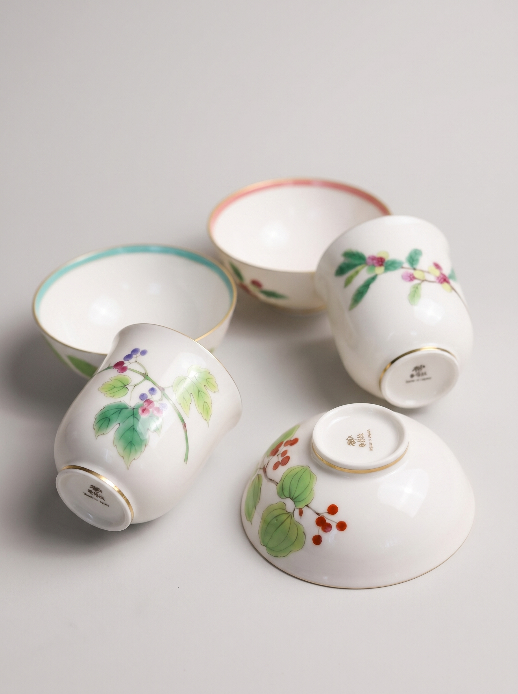 Set of four Japanese koransha porcelain cups with floral designs on a light gray background