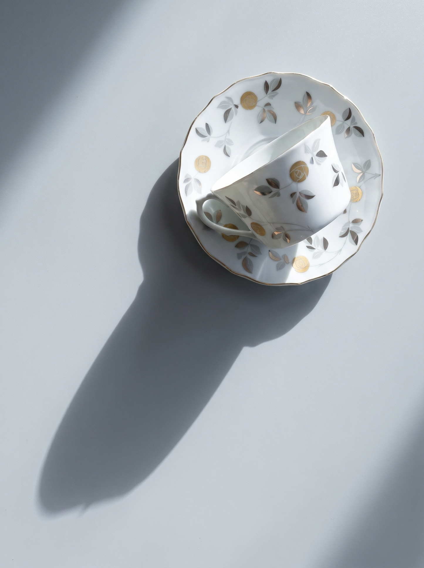 Decorative white teacup with gold floral patterns on a light gray background