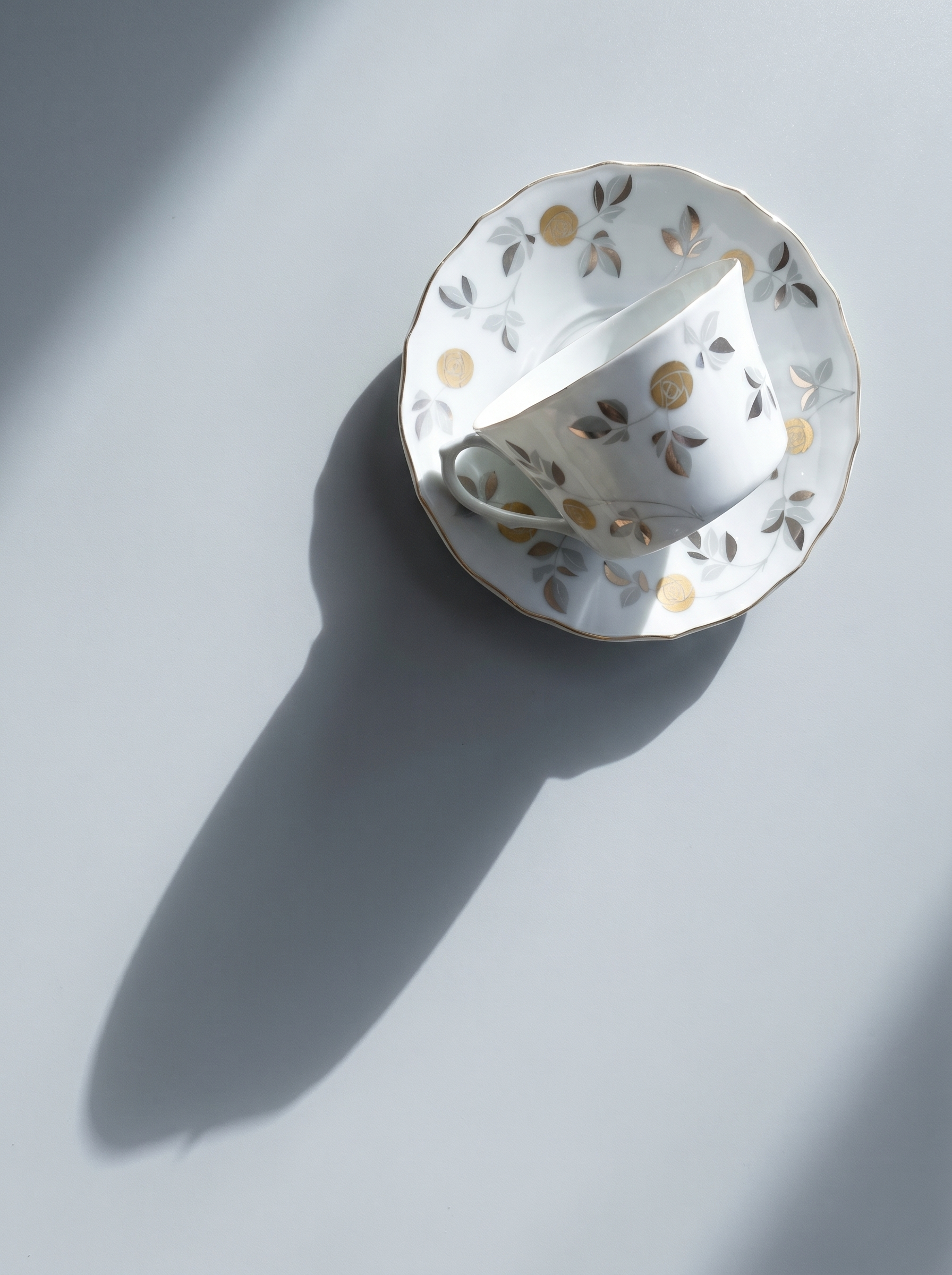 Decorative white teacup with gold floral patterns on a light gray background