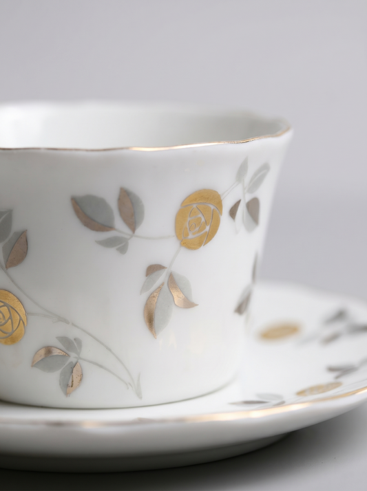 close up of Japanese koransha porcelain tea cup with a saucer and with gold and silver design on a light gray background