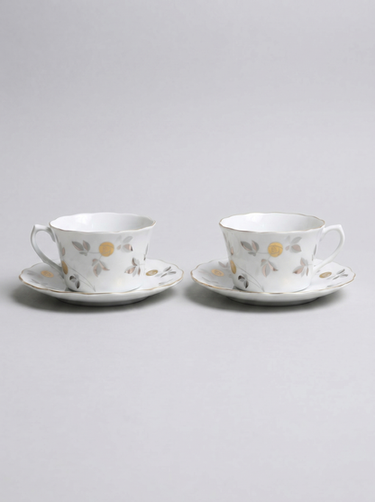 Two Japanese koransha porcelain tea cups with saucers and with gold and silver design on a light gray background