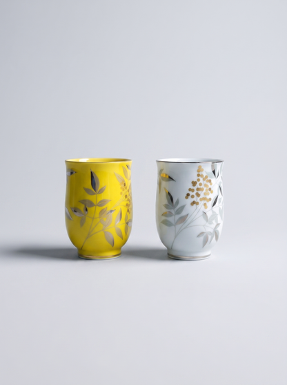 Two ceramic cups with floral designs on a light gray background