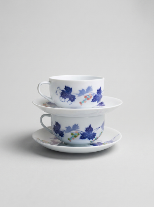 Two stacked Japanese porcelain cups with floral design on a light gray background