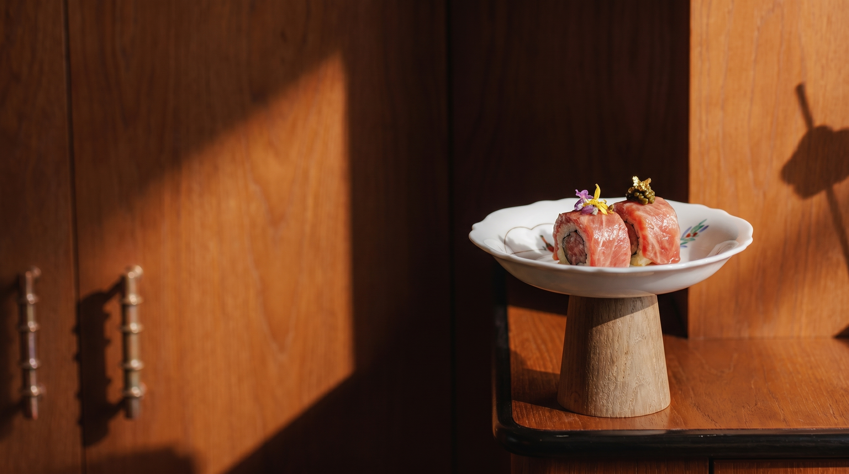 japanese koransha porcelain shallow plate with signature tuna rolls in modern restaurant interior