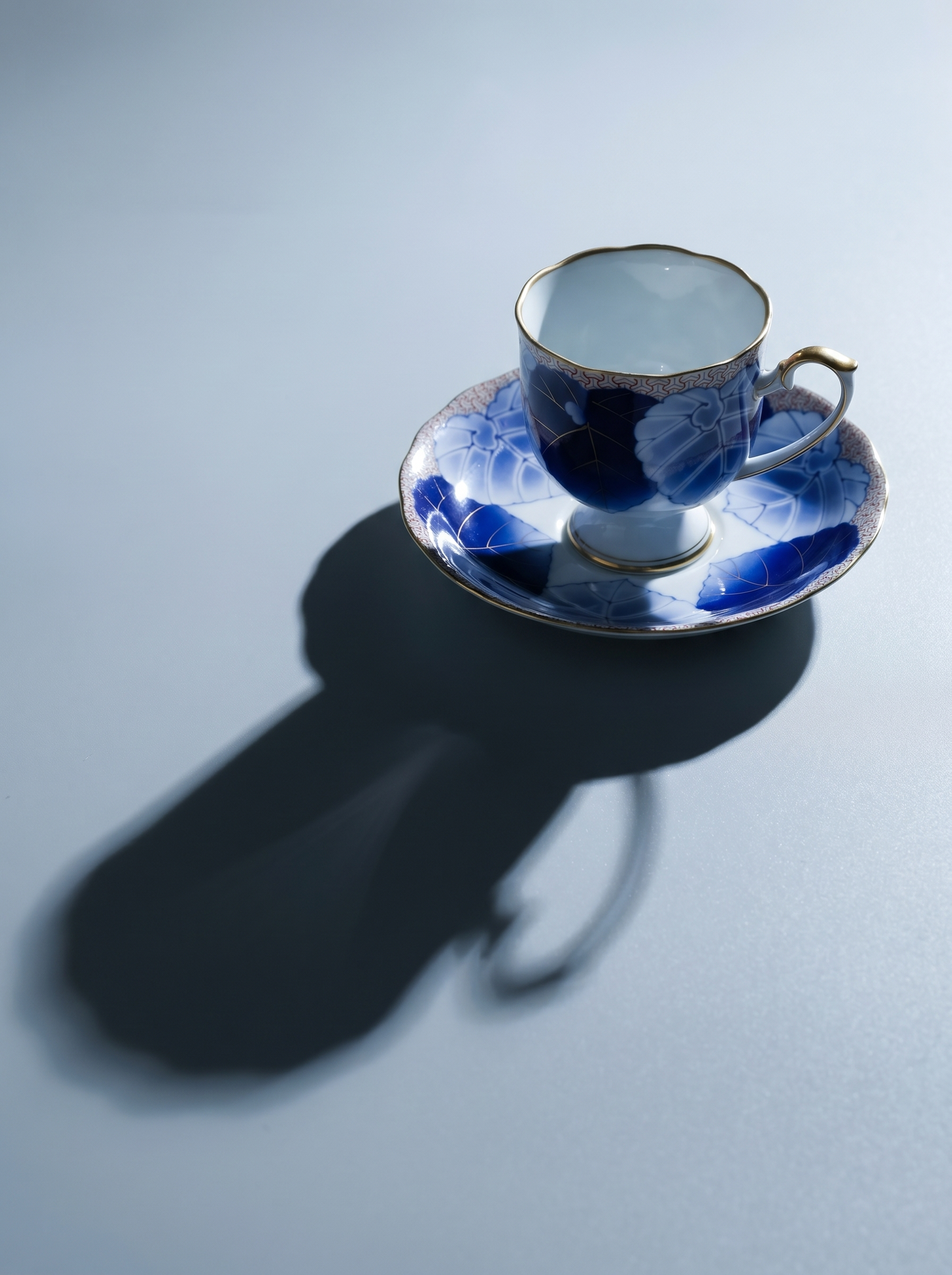 Blue and white porcelain teacup and saucer on a light gray background