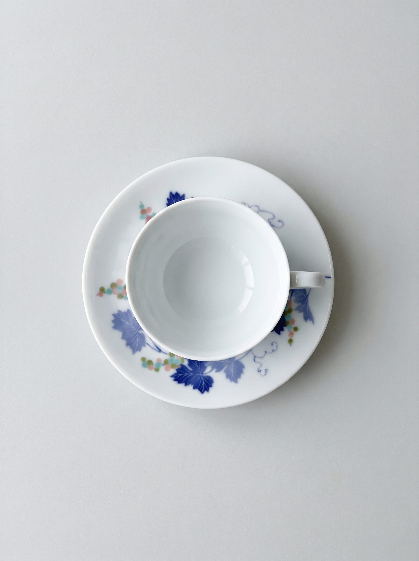 Cup and saucer with floral design on a light gray background top view