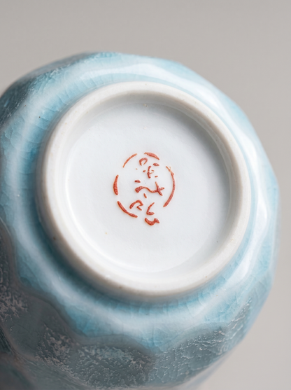 Ceramic cup with a blue glaze and red Japanese stamp on a gray background
