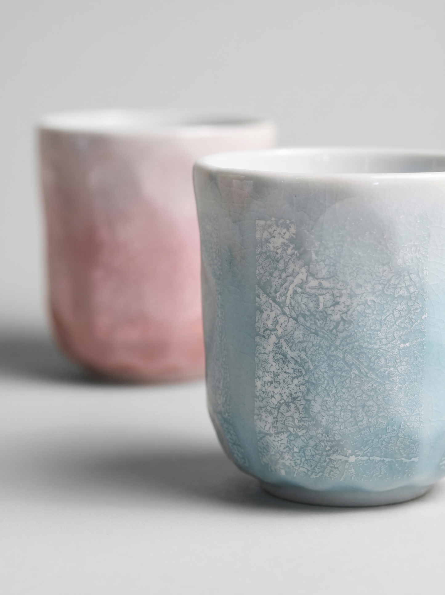 Two ceramic cups with ginsai finish surfaces on a light gray background