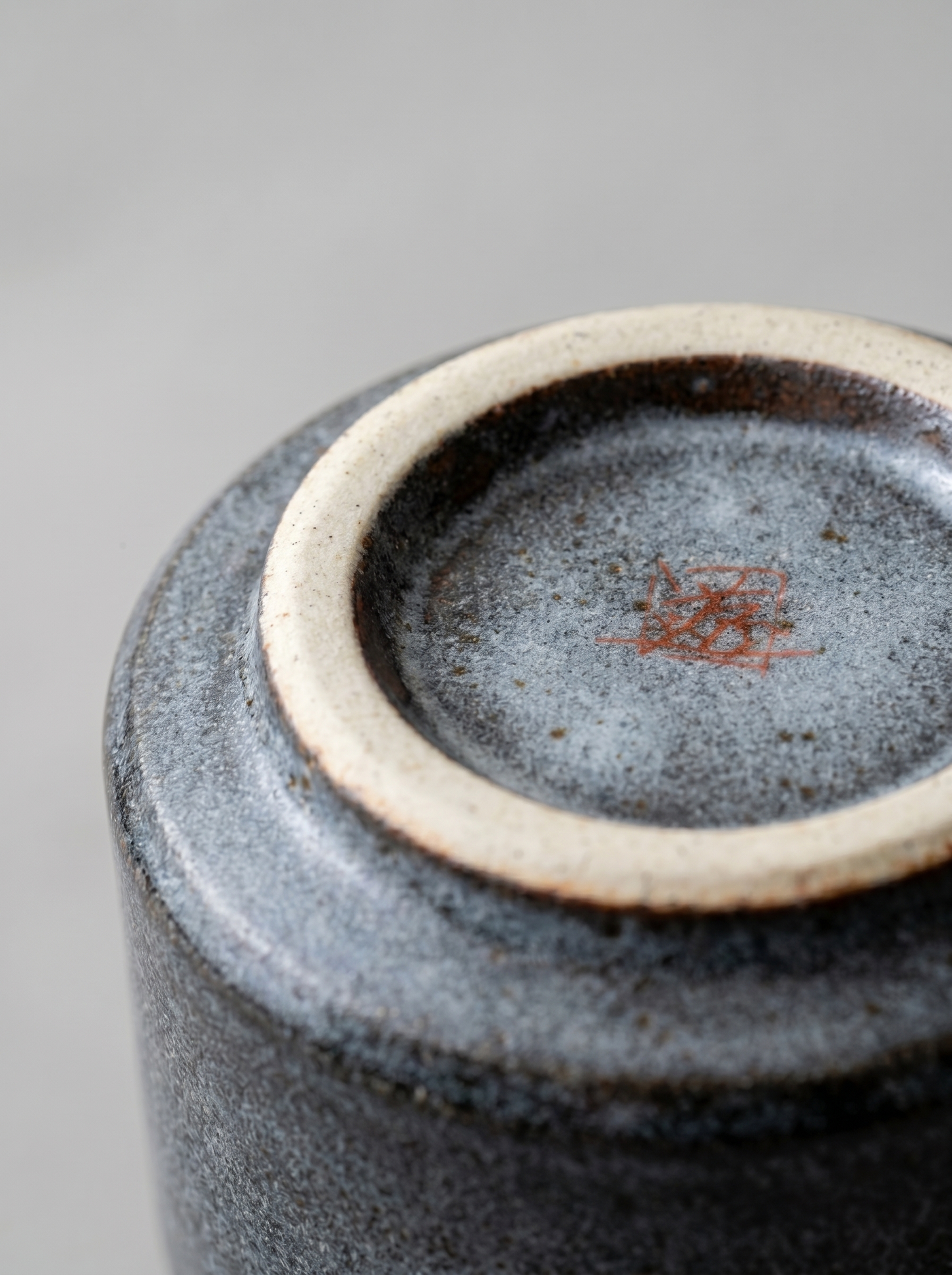 Close-up of a ceramic cup with a marking on a gray background