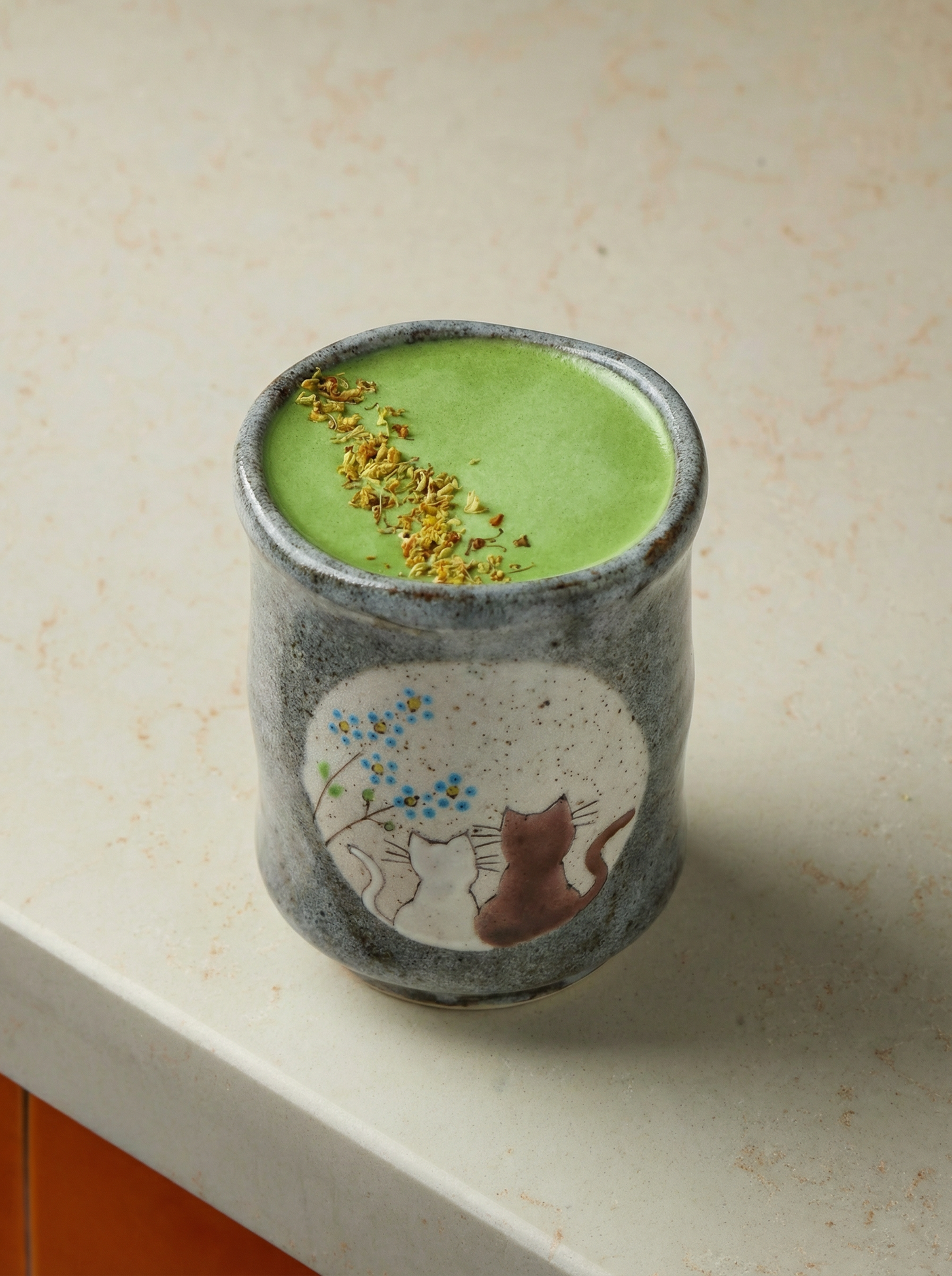 Japanese ceramic teacupswith no handle with a cats in sunny spot yunomi design filled with matcha latte on a beige background