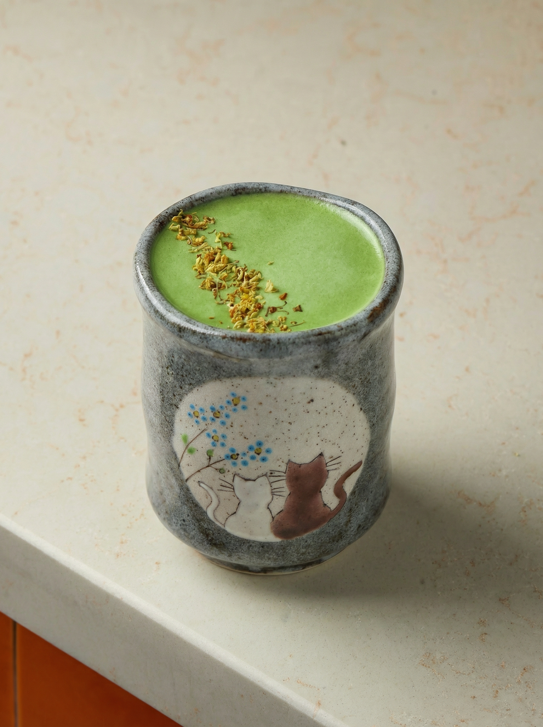 Japanese ceramic teacupswith no handle with a cats in sunny spot yunomi design filled with matcha latte on a beige background