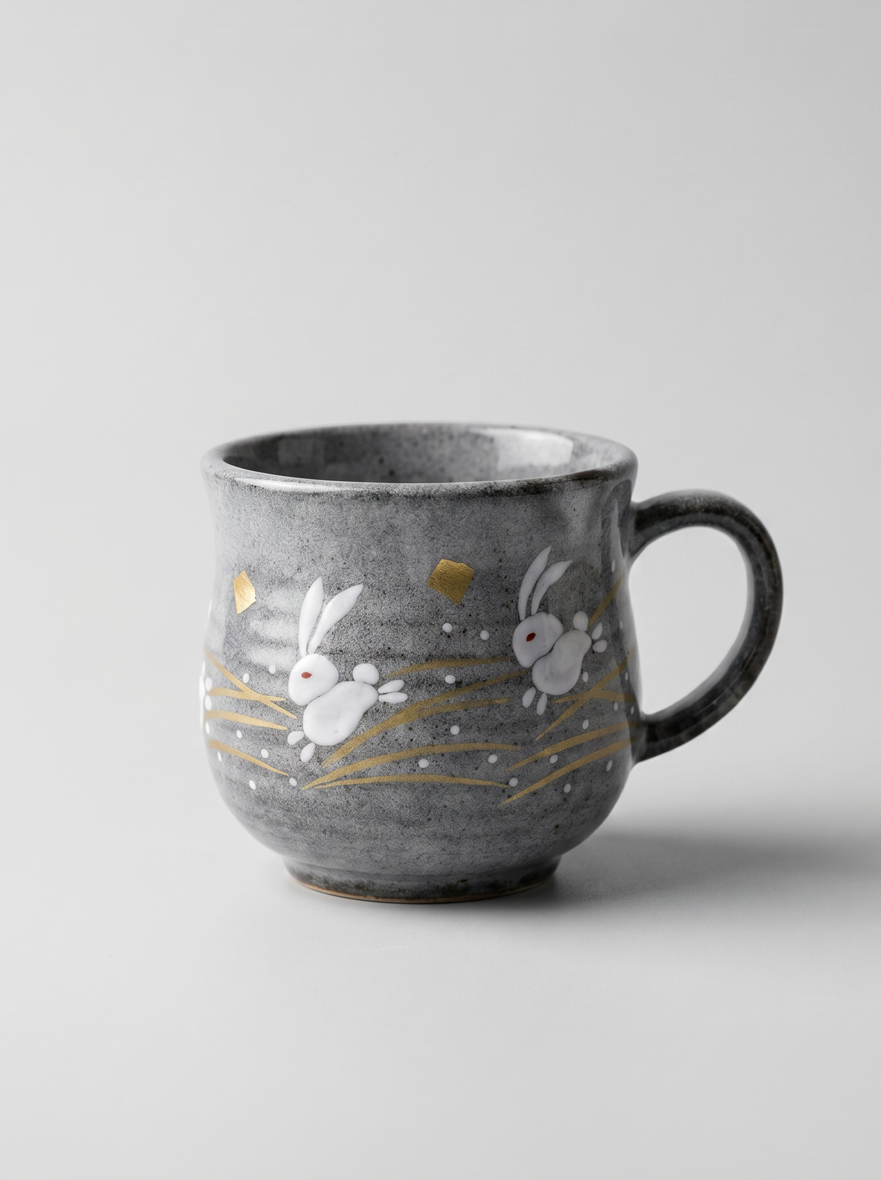 Japanese kutani ceramic teacup with a short handle with golden moon and rabbit design for tea, matcha latte, coffee, hojicha on a light grey background, front-facing