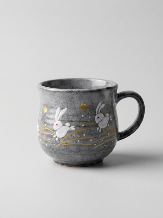 Japanese kutani ceramic teacup with a short handle with golden moon and rabbit design for tea, matcha latte, coffee, hojicha on a light grey background, front-facing