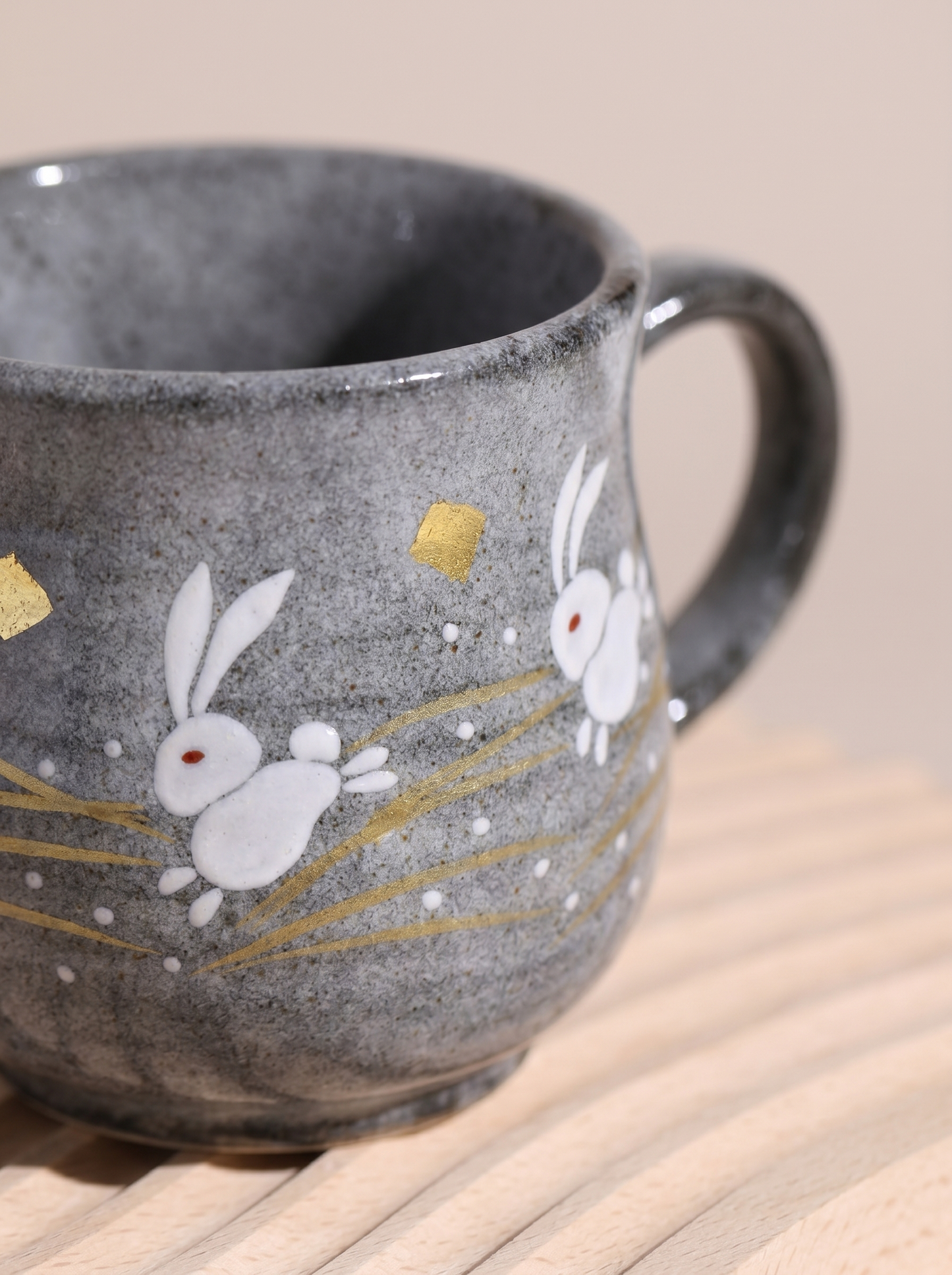 Close up of grey ceramic mug with rabbit and moon design on a wooden surface